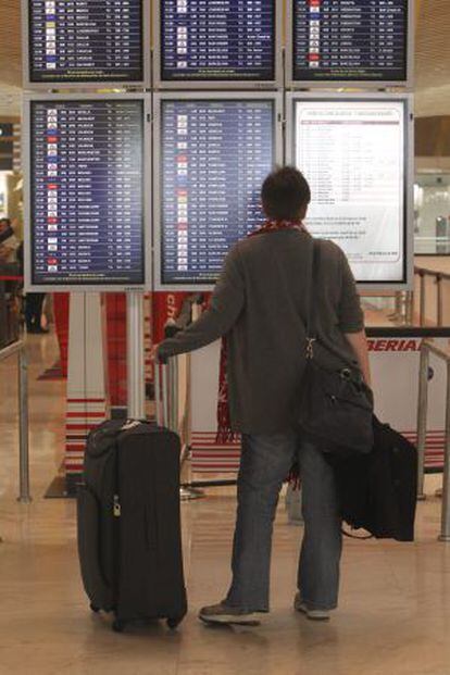 Un hombre mira los paneles de información de vuelos en el aeropuerto de Barajas en Madrid.