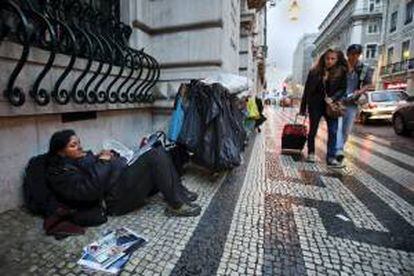 Una indigente descansa al frente del edificio del Banco Totta y Acores, en Lisboa, Portugal. EFE/Archivo