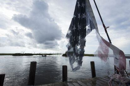 Una bandera rasgada de EE UU colgaba ayer de un mástil cerca de la isla de Jean Charles, en Luisiana.