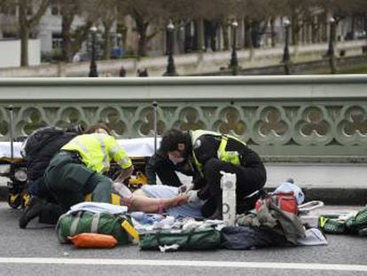 Miembros de los equipos de emergencia atienden a una de las v&iacute;ctimas del atentado en Londres.