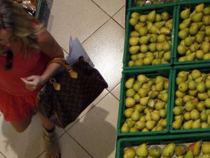 Una mujer compra frutas y verduras en un supermercado.