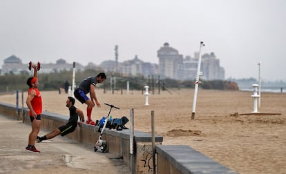 Tres hombres practican deporte en una playa de Valencia, este domingo.