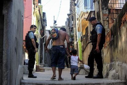 Dos policías observan a un hombre y su hijo durante un operativo en una favela de Río de Janeiro, en octubre de 2022.