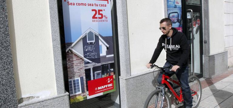 Un ciclista pasa delante de una oficina de Mapfre, en Madrid.