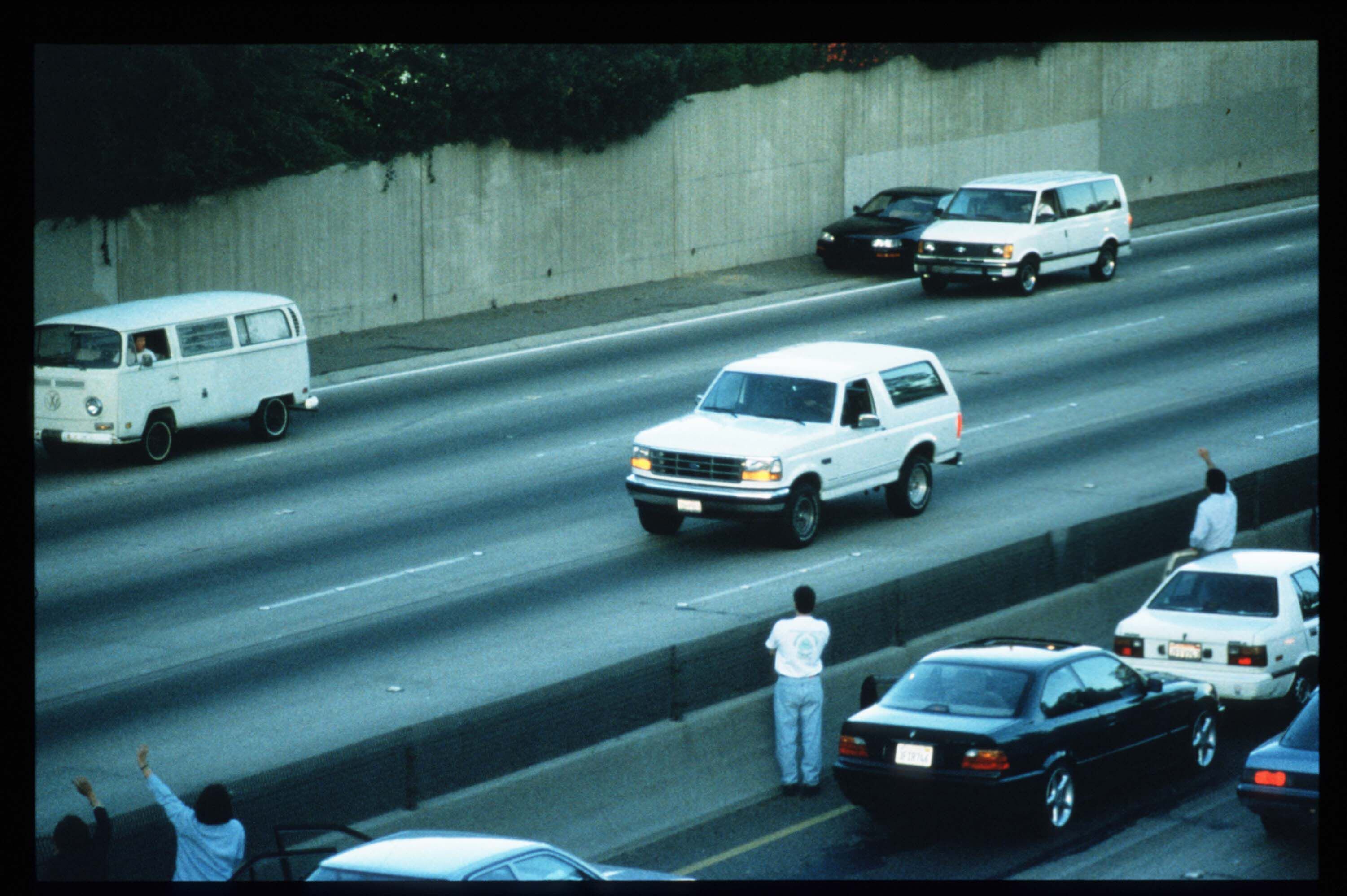 Automovilistas saludan a la estrella de fútbol americano O.J. Simpson mientras huye de la policía en la parte trasera de una camioneta Ford Bronco blanca, manejada por Al Cowlings, en Los Ángeles (EE UU), en junio de 1994.
