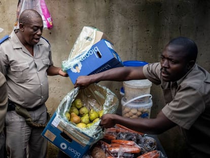 Dos agentes de la policía de Gauteng confiscan los alimentos que un hombre vende en su puesto callejero en el suburbio de Alexandra, en Johanesburgo, Sudáfrica, el 31 de marzo de 2020. Con el país en cuarentena, son muchos los se quedan sin medios de subsistencia si no pueden salir a la calle.