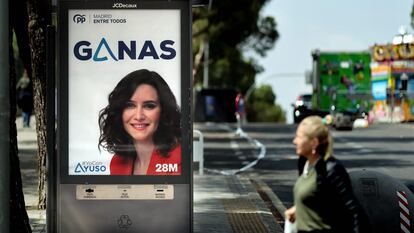 A woman walks past an electoral campaign poster of Partido Popular (PP) party's Madrid regional president and candidate Isabel Diaz Ayuso on May 25, 2023 in Madrid, ahead of the upcoming May 28 regional and municipal election. (Photo by Thomas COEX / AFP)