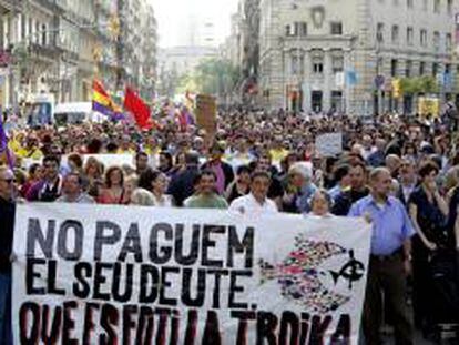 Varias personas sostienen una pancarta durante la manifestación contra la "troika" que esta tarde ha recorrido las calles de Barcelona.