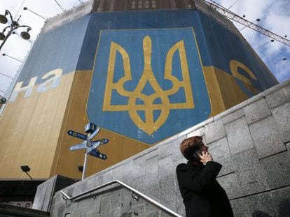 Un hombre habla por tel&eacute;fono junto a un edificio decorado con los colores nacionales junto a la plaza Maid&aacute;n en Kiev, este martes.