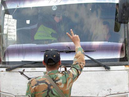 Soldados sirios hacen el símbolo de la victoria frente a un autobús que evacúa a rebeldes en Duma, a las afueras de Damasco.