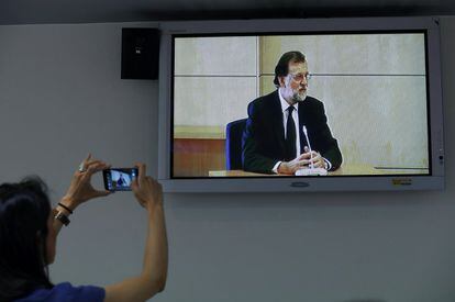 Una periodista hace una foto con su teléfono móvil a la pantalla donde se ve al presidente del Gobierno, Mariano Rajoy, testificar como testigo en el juicio del 'caso Gürtel', en la Audiencia Nacional en San Fernando de Henares, el 26 de agosto.
