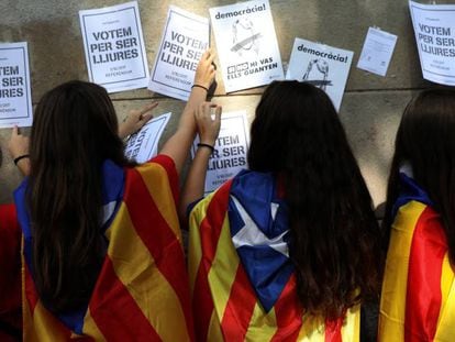 J&oacute;venes con esteladas pegan carteles de apoyo al refer&eacute;ndum. 