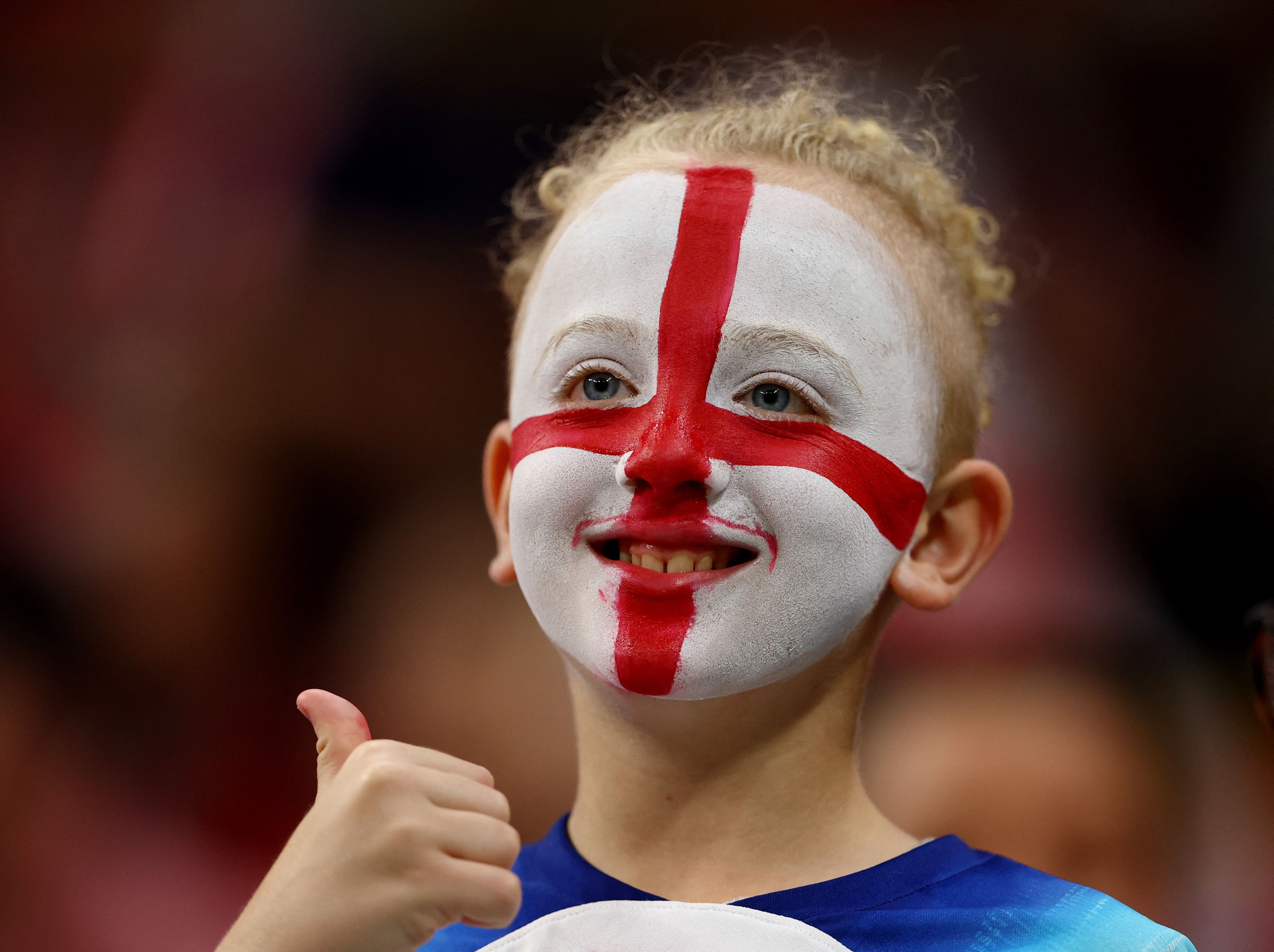 Un niño con el rostro pintado con la bandera de Inglaterra.