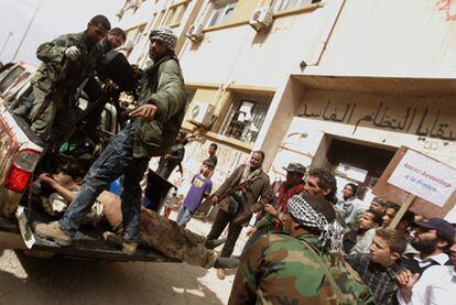 Varios rebeldes trasladan en Bengasi a un soldado de Gadafi herido y capturado. "Muchas gracias a Francia", reza una pancarta.