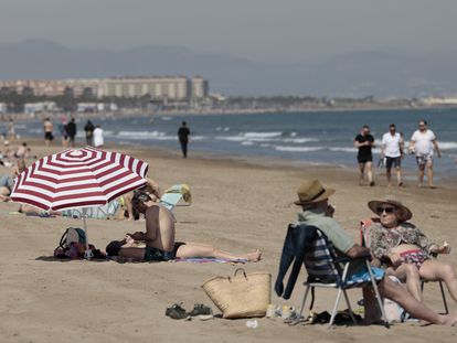 Gente tomando el sol en la playa de la Malvarrosa de Valencia, donde los termómetros rozan los 30 grados, este lunes.