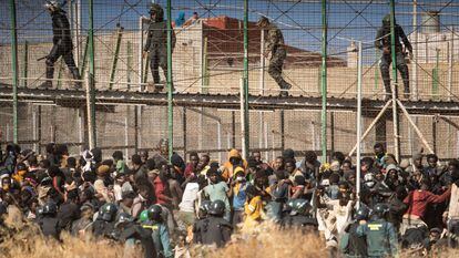 Inmigrantes y policías en la valla de Melilla, el 24 de junio.