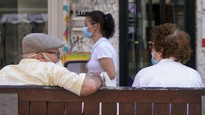 Una pareja de ancianos con mascarilla, sentada en un banco de Madrid el pasado julio.