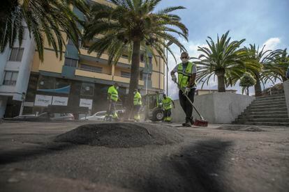 Un  equipo de limpieza procedente de Tenerife limpia la ceniza procedente del volcán en una plaza de Los Llanos.