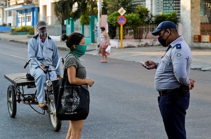 Un policía revisa la identificación de una mujer en La Habana, durante la cuarentena.