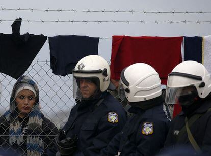 Una muijer mira a polic&iacute;as griegos en la frontera con Macedonia.
