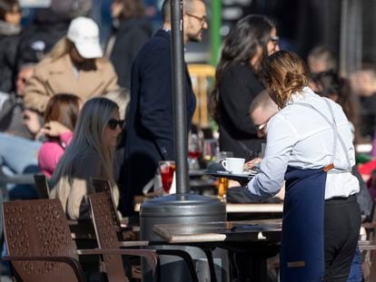 Una camarera recoge una mesa de la terraza de un bar del centro de Sevilla, este viernes.