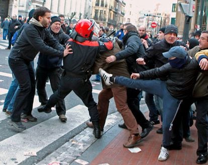 Un agente de la Ertzaintza forcejea con varios manifestantes ante un centro comercial de Bilbao durante la jornada de huelga general convocada por los sindicatos nacionalistas en el País Vasco, Cataluña, Navarra y Galicia.