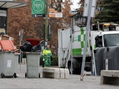 Un trabajador municipal junto a cubos de basura rebosantes en otoño de 2013.