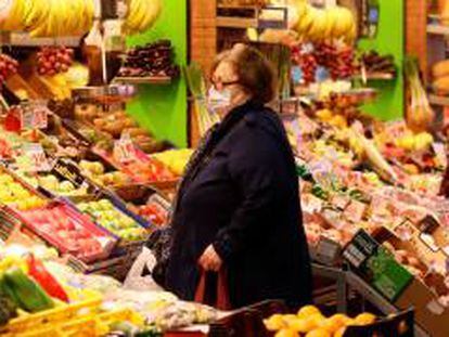 Una mujer compra en un puesto de frutas y verduras.