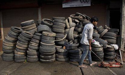 Un joven indio junto a neumáticos para reciclaje en Gauhati, India.