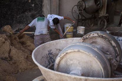 Obreros de la construcción preparan la mezcla con arena y cemento.
