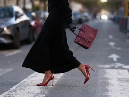 Una mujer pasea en París con unos zapatos de tacón rojos de Saint Laurent.