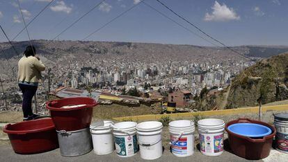 Una mujer contempla la ciudad de La Paz; a sus espaldas, numerosos cubos para almacenar agua.