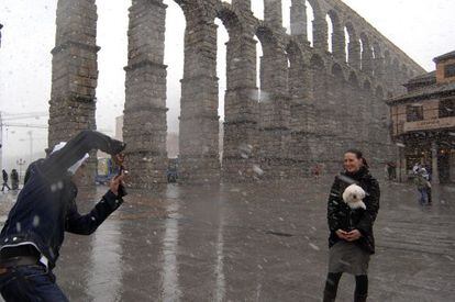 Dos turistas se hacen fotos bajo la nieve en Segovia.