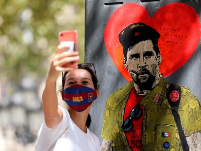 Una mujer se toma una fotografía con el grafiti de Messi vestido como el Che Guevara.