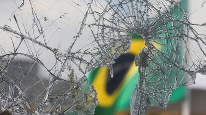 Una bandera brasileña se ve a través de vidrios rotos luego de los disturbios en el Palacio Planalto, en Brasilia, Brasil, el 10 de enero de 2023.