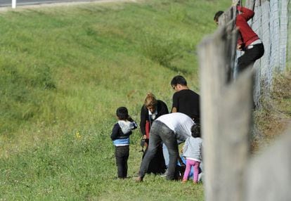 Los refugiados cruzan el muro para abandonar el centro de recepción de inmigrantes en Roszke, Hungría.