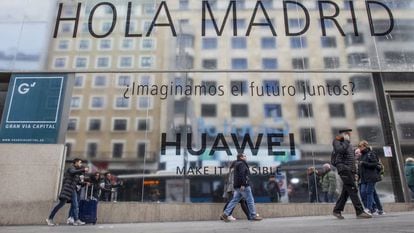 Varias personas pasean por la Gran Vía de Madrid, junto a la futura tienda de Huawei.