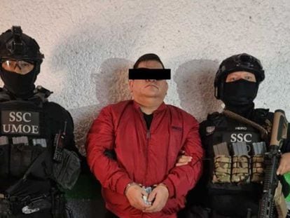 Dos elementos de la Secretaría de Seguridad Ciudadana resguardan a José Bernabé Brizuela, líder de la banda Los mezcales, tras su detención en Ciudad de México, el 18 de agosto de 2022.