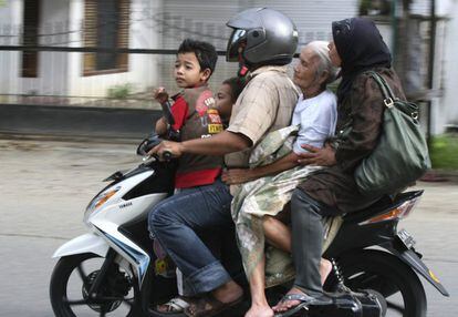Un hombre traslada a miembros de su familia en una motocicleta, tras la alerta por riesgo de tsunami en Banda Aceh.