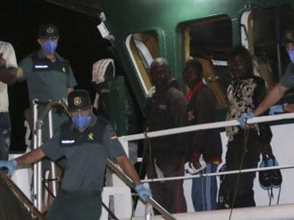 Diversos immigrants rescatats dimarts quan navegaven en una pastera esperen per desembarcar en arribar al port d'Almeria.