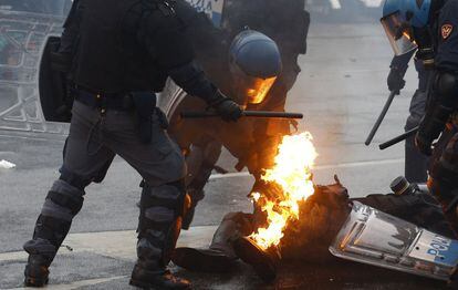 Un policía ayuda a un compañero alcanzado por un cóctel molotov durante el enfrentamiento con los manifestantes.