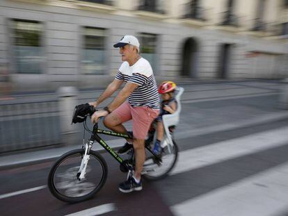 Un se&ntilde;or mayor circula con un ni&ntilde;o peque&ntilde;o en el transport&iacute;n por el carril bici de la calle de Alcal&aacute; de Madrid. 