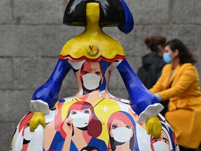 Varias personas pasan junto a una 'menina', decorada con sanitarios con mascarilla, este viernes en Madrid.