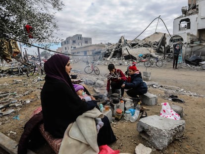 Una familia se reúne alrededor del fuego frente a su casa destruida, a causa de los ataques israelíes, en Jan Yunis este martes.