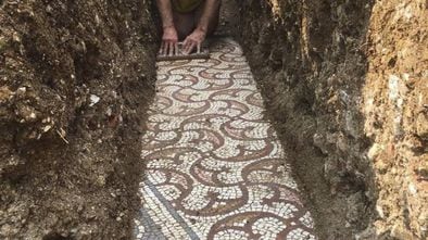 Un hombre realiza tareas de limpieza del mosaico romano hallado en Roma. 