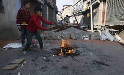 Niños intentan avivar un fuego cerca de una barricada en el centro de Srinagar, la principal ciudad del valle de Cachemira, este jueves. 
 
 
