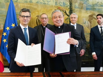 El ministro de la Presidencia, Félix Bolaños (a la izquierda), intercambia documentos con el nuncio en España, el arzobispo Bernardito Auza, durante un encuentro celebrado este miércoles en Madrid. Al fondo, en el centro, Juan José Omella, presidente de la Conferencia Episcopal.