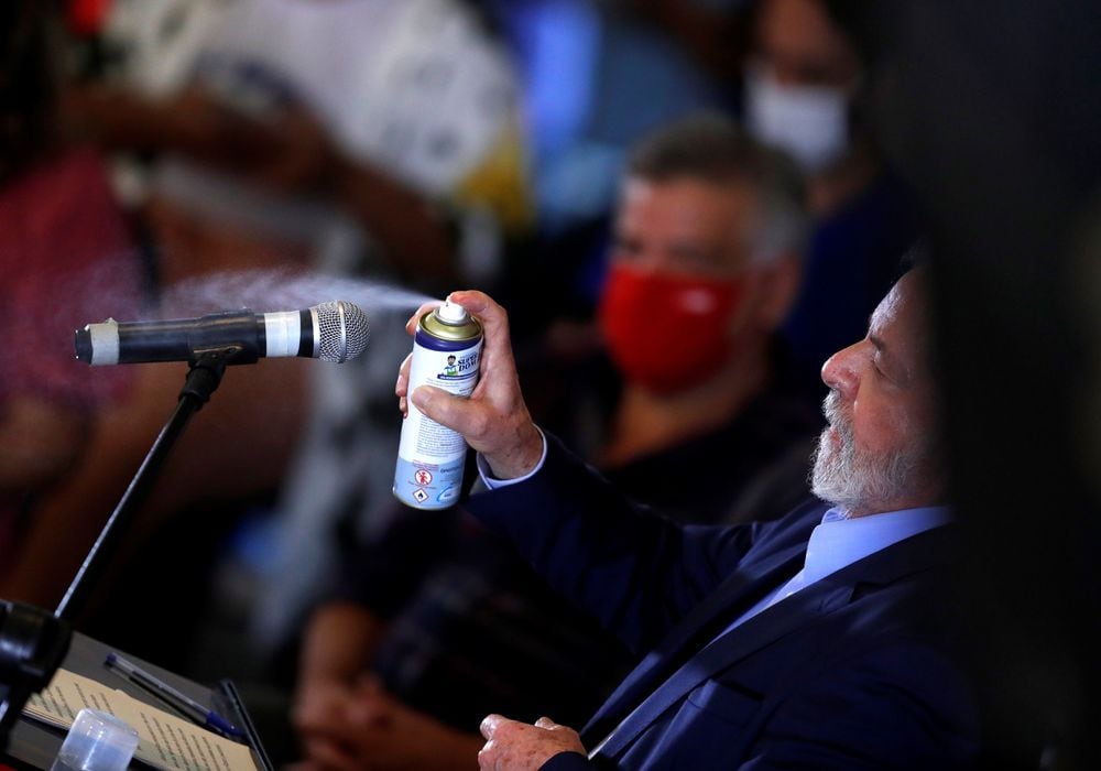 Lula da Silva rocía desinfectante al micrófono durante la rueda de prensa.