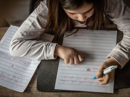 Una niña escribe a mano en su habitación.