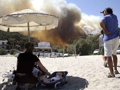 Una familia observa el fuego desde una playa en la isla de Eubea, donde se ha refugiado.